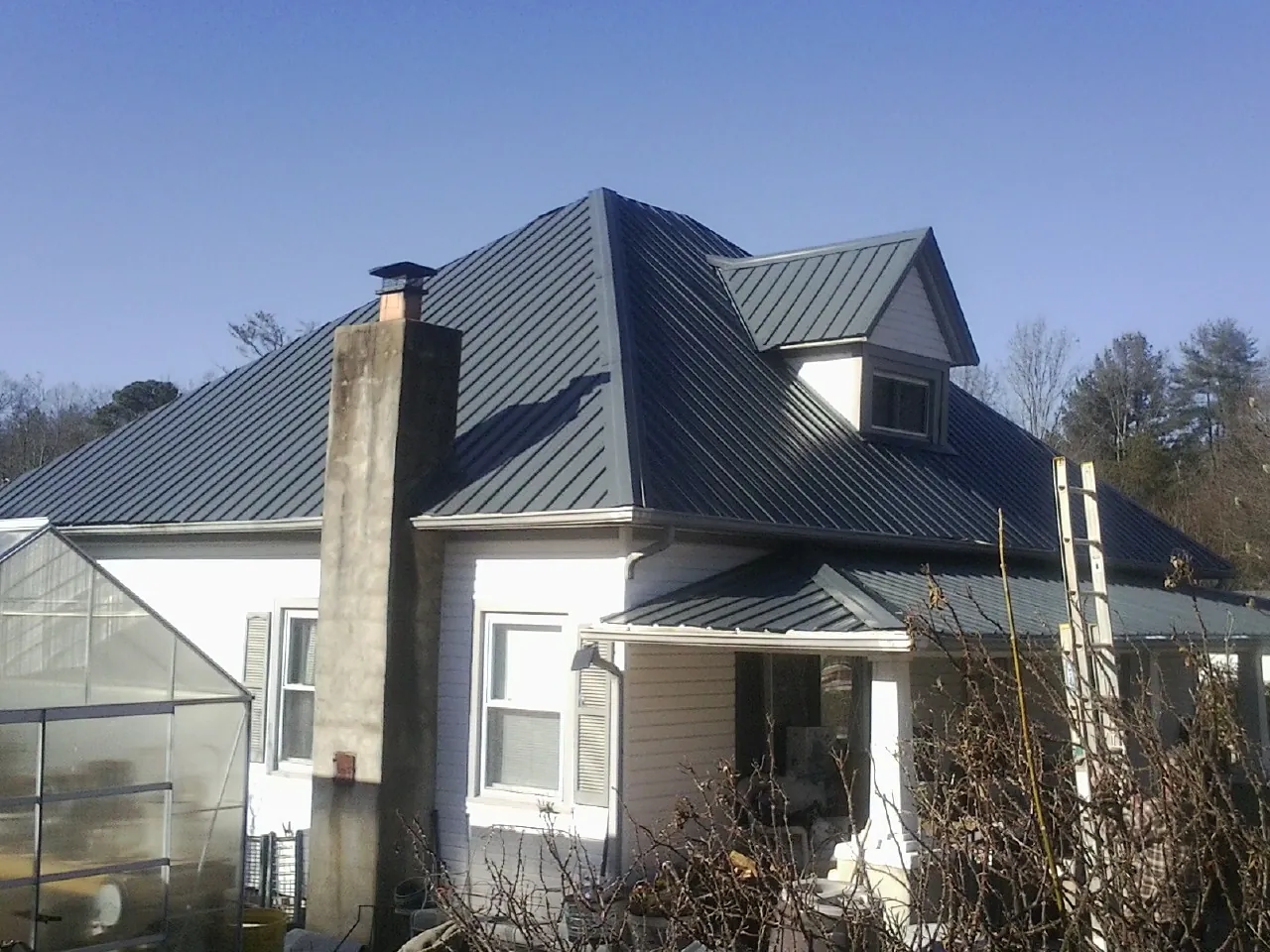Dark blue standing seam metal roof on a white farmhouse with dormer — Slate & Tile Roof Repair by Roofing Brothers in Mount Braddock