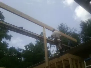 Carpenter setting a ridge beam over a new addition frame — Ice Dam Removal by Roofing Brothers in Mount Braddock