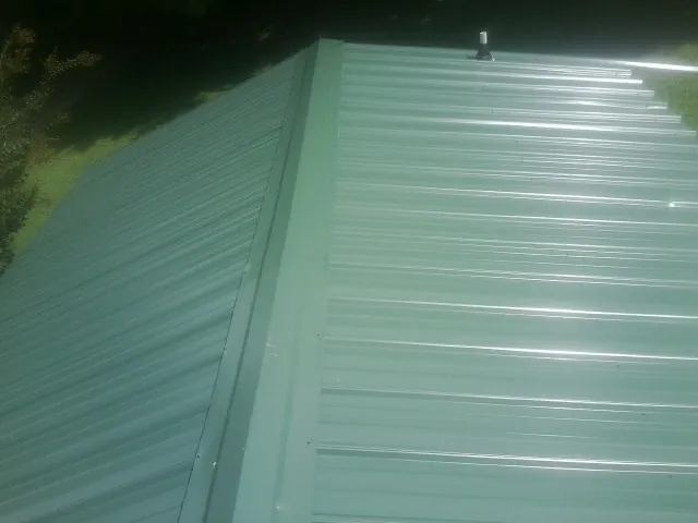 New green metal panels meeting at the ridge of a roof — Flat Roof Repair work by our crew in Mount Braddock
