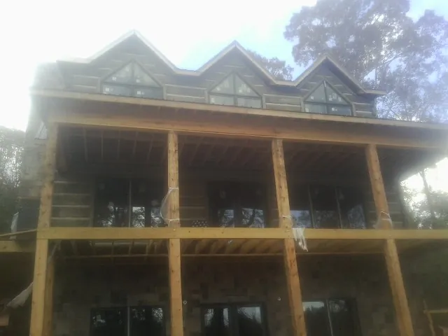Dormers and porch framing on a large log home under construction — Roof Coating work by our crew in Mount Braddock