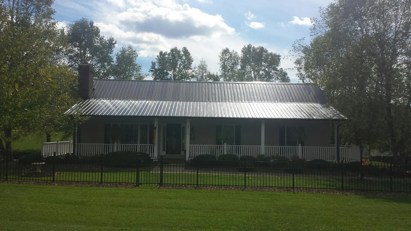 Gray metal roof on a brick ranch with a full width front porch — Gutter Guard Installation work by our crew in Mount Braddock